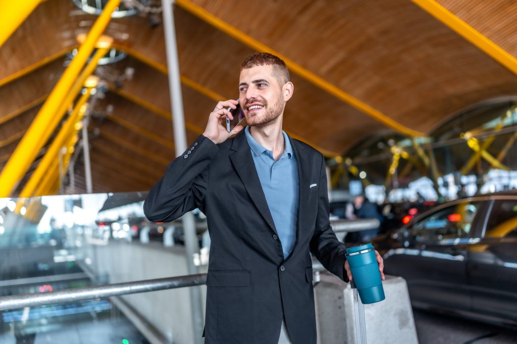 Businessman talking on phone at airport with luggage